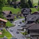 Picturesque Swiss village with cottages and winding roads in lush greenery.