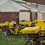 A collection of Deutsche Post bicycles parked outside a tent, representing eco-friendly delivery options.